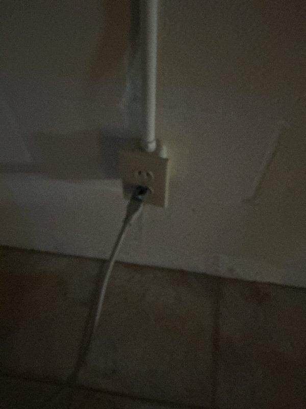 Conducted electrical inspection of wall receptacle and verified proper installation of outlet with connected load. Observed adjacent water meter and plumbing system during inspection, noting no electrical hazards present in utility area.