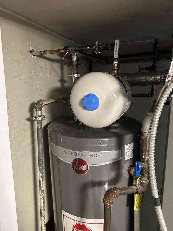 Completed flue repair for water heater system and installed new expansion tank on Rheem Performance unit. Repaired damaged ceiling and ductwork connection where galvanized steel components meet the air handler. Two-person crew executed all necessary plumbing connections including shut-off valve installation and proper pipe securing to ensure code-compliant operation.