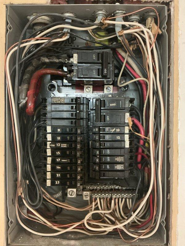 Performed comprehensive electrical panel inspection, documenting the condition of a dual-column circuit breaker panel with multiple numbered breakers (9-23). Observed bundled wiring configuration with white, red, and black conductors, noting some disorganization in wire routing but confirming functional operation of all components. Inspected ceiling access point above panel for proper conduit connections and structural integrity.