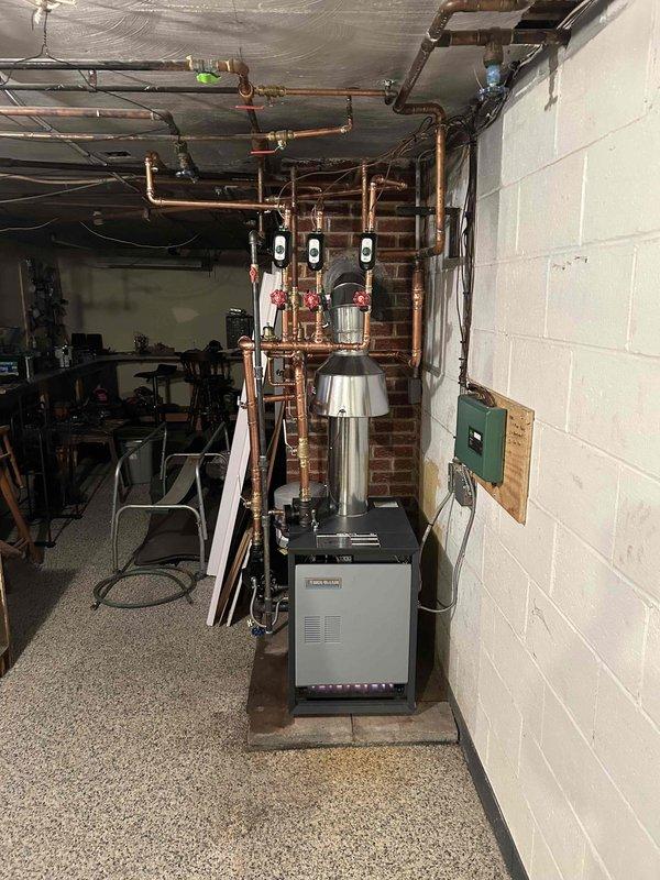 Successfully completed installation of a new boiler system with comprehensive copper piping network throughout the basement mechanical room. System includes multiple digital control devices mounted on vertical pipes, proper exhaust flue installation, and connection to the existing electrical panel. All components were properly secured, tested, and verified to be in optimal working condition.