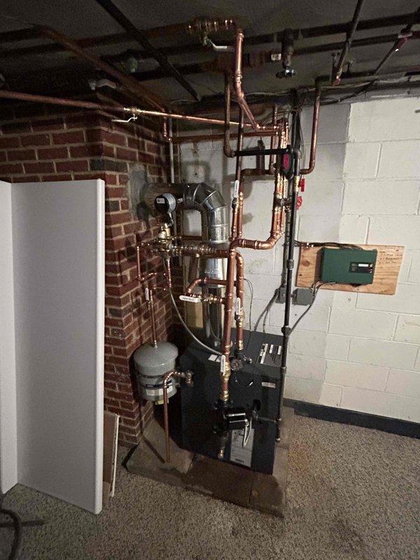 Successfully completed installation of a new boiler system with comprehensive copper piping network throughout the basement mechanical room. System includes multiple digital control devices mounted on vertical pipes, proper exhaust flue installation, and connection to the existing electrical panel. All components were properly secured, tested, and verified to be in optimal working condition.