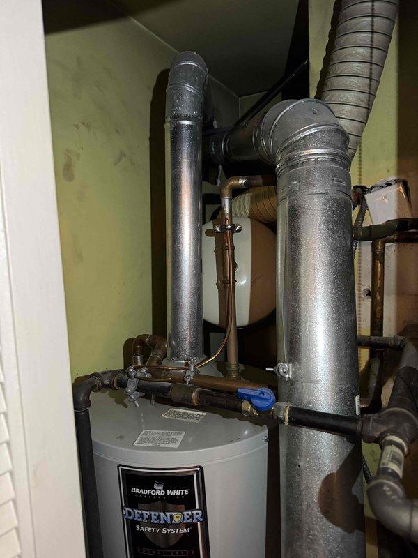 Completed scheduled heating maintenance on residential HVAC system. Performed combustion analysis on furnace with EM201B digital testing device, recording negative pressure readings of -0.044. Inspected adjacent Bradford White "Defender" water heater installation including ventilation ducts, supply lines, and gas connections, confirming proper setup and functionality.