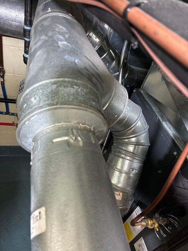 Conducted inspection of thermostat system, noting Energizer AA batteries in place and operational. Examined ductwork connections in mechanical room, identifying galvanized sheet metal ducts with visible joints and seams alongside copper piping. Provided replacement options for furnace system based on observed condition of components.