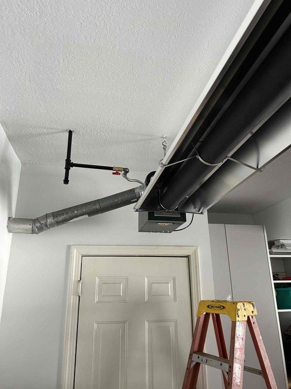 Completed installation of ceiling-mounted garage heater with proper ductwork connections. Installed black rectangular supply plenum with galvanized round takeoff, ensuring secure mounting to textured ceiling. Final inspection confirmed proper functionality and collected payment.