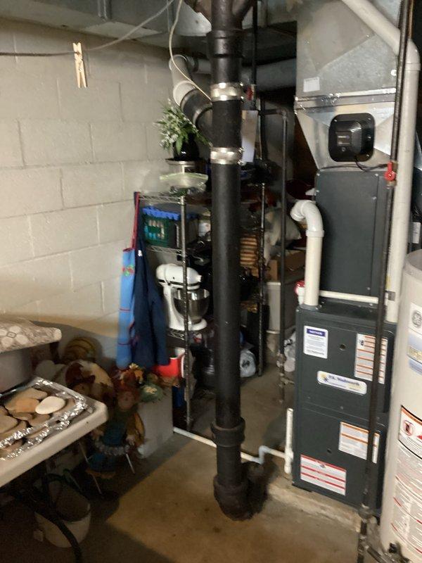 Conducted comprehensive plumbing inspection of basement utility area, focusing on HVAC equipment and water heater installation. Identified significant rust and corrosion at pipe elbow joint where horizontal metal pipe connects to vertical pipe, with potential moisture issues that require attention.