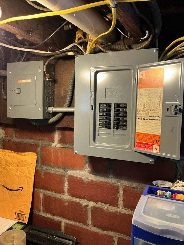Inspected non-operational boiler system in basement utility area. Unit is significantly aged and has completely failed, requiring full replacement. Photos documented the existing electrical panel installation and current boiler configuration with associated piping and pressure components for replacement estimation purposes.