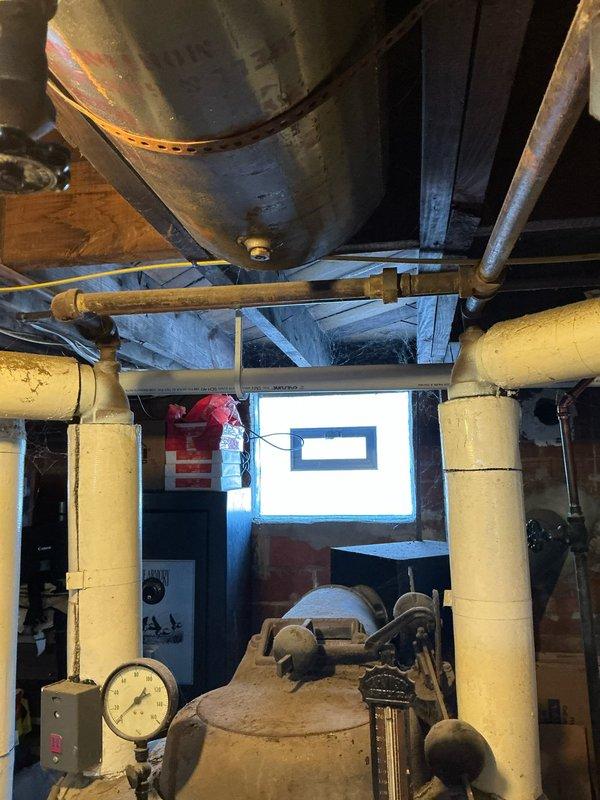 Inspected non-operational boiler system in basement utility area. Unit is significantly aged and has completely failed, requiring full replacement. Photos documented the existing electrical panel installation and current boiler configuration with associated piping and pressure components for replacement estimation purposes.