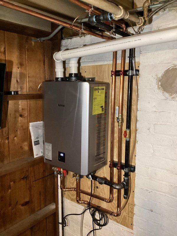 Successfully installed a Rinnai tankless water heater with complete copper piping network, including necessary valves and connections. Mounted unit securely to wooden wall structure and installed proper PVC ventilation system and condensate pump. All connections were tested and system is functioning as designed.