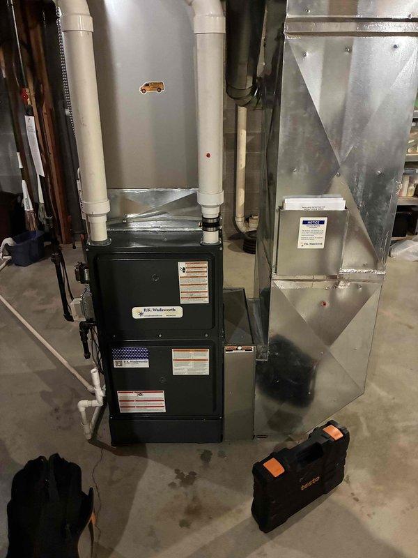 Completed routine heating maintenance service on residential furnace system. Inspected black furnace unit, associated PVC ventilation pipes, and metal ductwork assembly for proper operation and safety compliance. All components functioning correctly with no issues identified during this scheduled preventative maintenance visit.