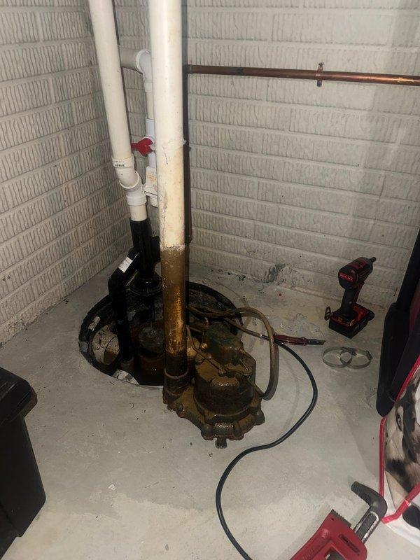 Completed installation of a new sump pump system in basement utility area, replacing the previous unit which showed significant rust and corrosion. Installation included proper connection of PVC discharge pipes, check valve installation, and verification of system operation to ensure effective basement water management.