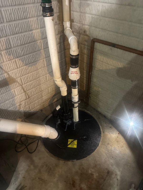 Completed installation of a new sump pump system in basement utility area, replacing the previous unit which showed significant rust and corrosion. Installation included proper connection of PVC discharge pipes, check valve installation, and verification of system operation to ensure effective basement water management.