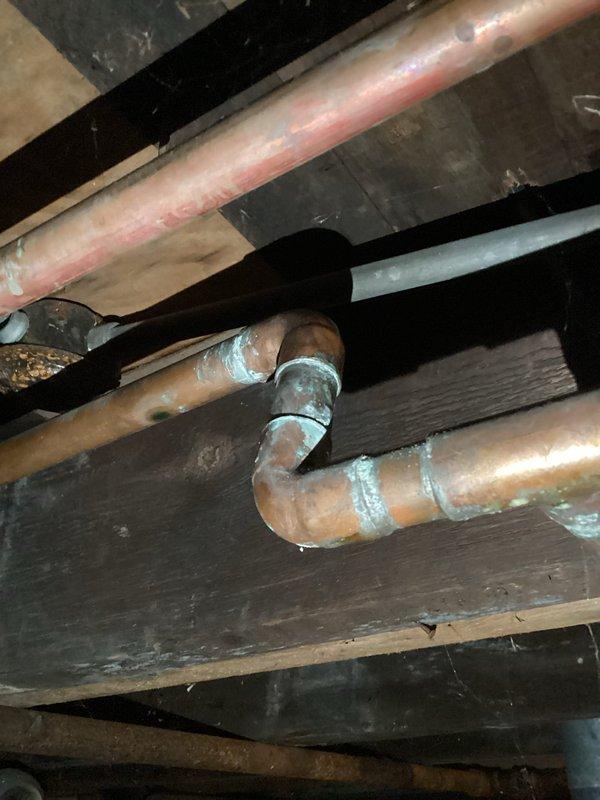 Performed diagnostic assessment of burst copper pipes in basement ceiling that caused ceiling collapse. Inspection revealed oxidized copper supply lines with compromised joints showing signs of failure at T-junction connection. Documented evidence of water damage to surrounding wooden structural members with photographic evidence suitable for insurance claim documentation.