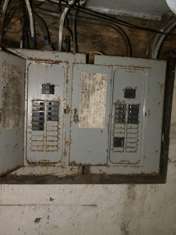 Conducted comprehensive assessment of severely deteriorated electrical panel showing significant rust damage and aging infrastructure. Inspection revealed outdated wiring system with potential safety hazards, including corroded connections in utility area with exposed pipes and structural elements. Recommended complete rewiring and panel replacement to bring electrical system up to current code requirements.