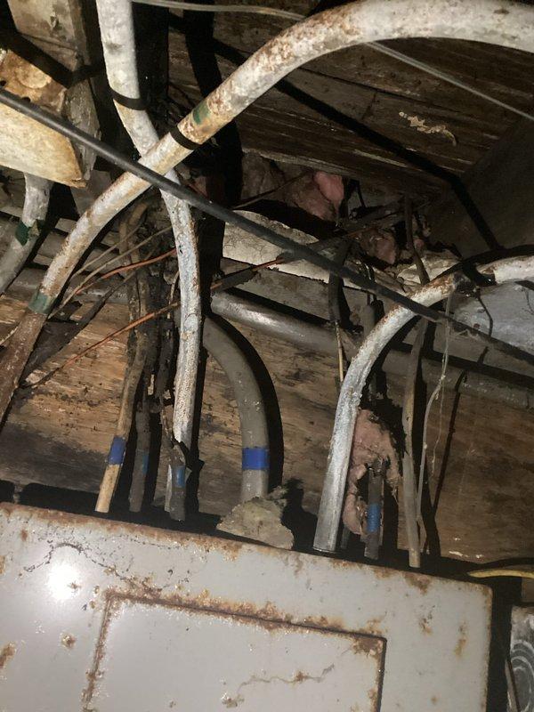 Conducted comprehensive assessment of severely deteriorated electrical panel showing significant rust damage and aging infrastructure. Inspection revealed outdated wiring system with potential safety hazards, including corroded connections in utility area with exposed pipes and structural elements. Recommended complete rewiring and panel replacement to bring electrical system up to current code requirements.