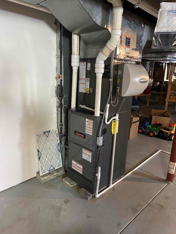 Successfully installed and commissioned a complete HVAC system consisting of a 96% efficient furnace with integrated air conditioning and humidifier. System includes properly sealed ductwork, PVC ventilation piping, and all necessary connections mounted on a concrete pad in the utility area.