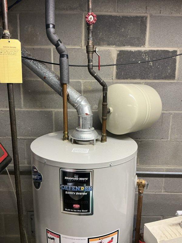 Performed scheduled preventative maintenance on residential heating system. Inspected furnace interior components including gas valve, motor assembly, control board, and wiring connections - all found in working order with minor corrosion noted on lower cabinet. Also examined adjacent Bradford White water heater with expansion tank, confirming proper installation with no leaks or deterioration present.