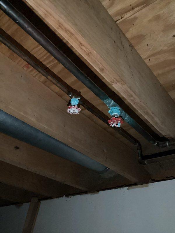Completed routine plumbing inspection with focus on water heater system and shut-off valves. Inspected Bradford White water heater installation including copper supply lines, PVC drain pipe, and gas connection. Verified proper function of main water shut-off valves located on pipes mounted to ceiling joists.