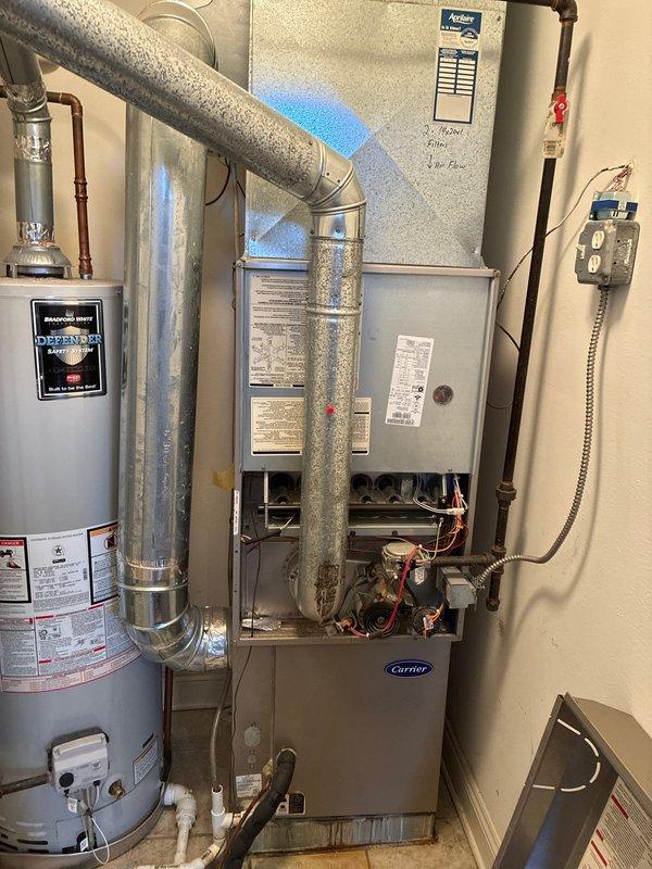 Conducted full system evaluation of existing Carrier HVAC equipment in utility closet. Inspected furnace with front panel open to assess internal components including control board, wiring and mechanical elements. Documented condition of ductwork, connections, and adjacent water heater to prepare comprehensive system replacement options for client consideration.