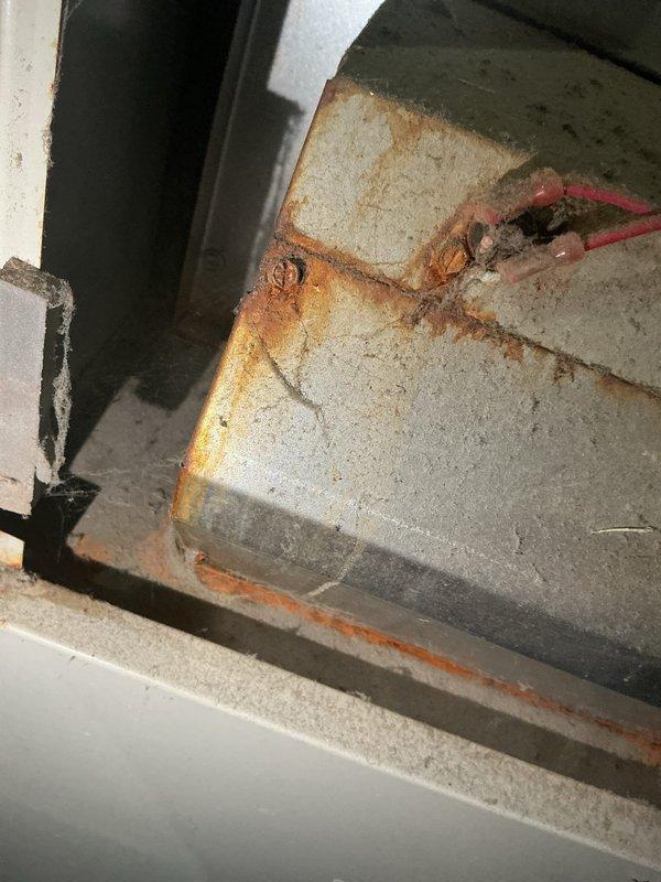 Performed routine heating tune-up and inspection of aging HVAC system. Noted significant rust and corrosion on metal housing components, particularly along edges and seams, indicating potential moisture exposure. Observed substantial dust accumulation on pressure/temperature gauge and internal components requiring cleaning to maintain optimal system performance.