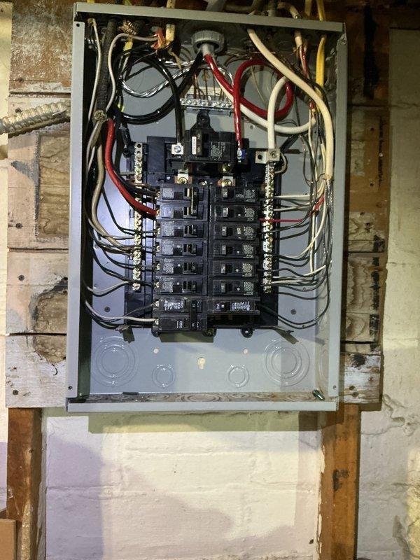 Conducted comprehensive electrical inspection of main service panel, documenting proper circuit breaker connections and wire terminations. Also photographed and examined adjacent plumbing system with multiple valves, copper/iron piping configurations, and associated mechanical infrastructure for documentation purposes.