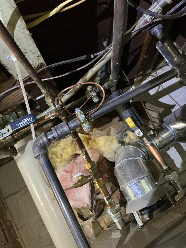 Conducted comprehensive electrical inspection of main service panel, documenting proper circuit breaker connections and wire terminations. Also photographed and examined adjacent plumbing system with multiple valves, copper/iron piping configurations, and associated mechanical infrastructure for documentation purposes.