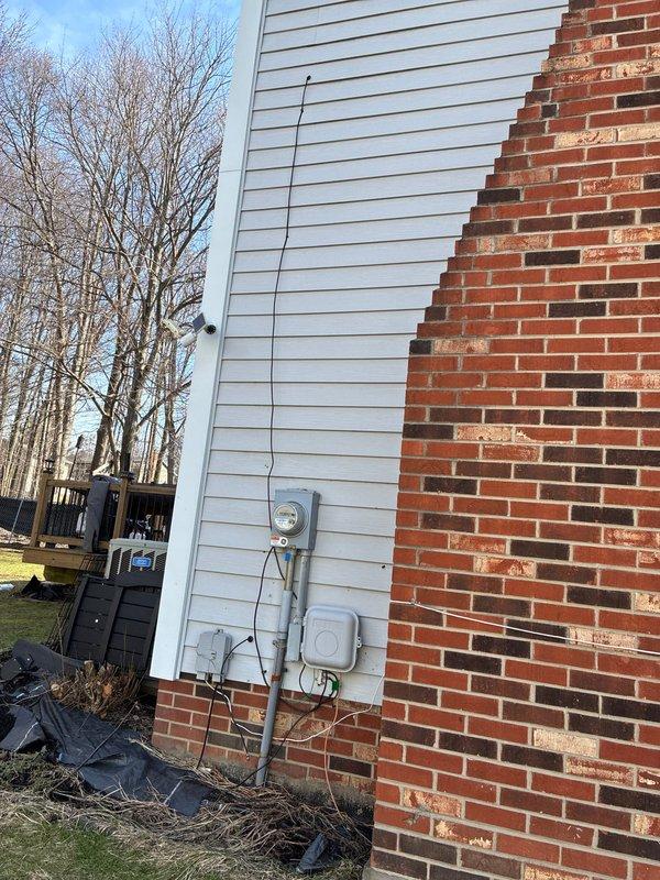 Conducted full system options evaluation for HVAC replacement. Inspected existing outdoor condensing unit housed within wooden enclosure adjacent to deck. Documented current electrical connections and meter configuration on exterior wall where brick meets vinyl siding. Photos taken of installation area and utility access points for proper system sizing and installation planning.