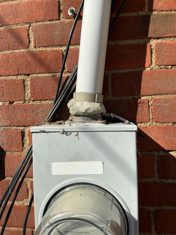 Conducted site assessment for electrical reconnection after customer reported downed wiring between residence and utility pole. Inspected outdoor electrical meter box mounted on brick exterior wall showing deteriorated sealant at conduit connection point, and documented condition of adjacent HVAC equipment with compromised clearance. Provided comprehensive estimate for rewiring and service restoration.