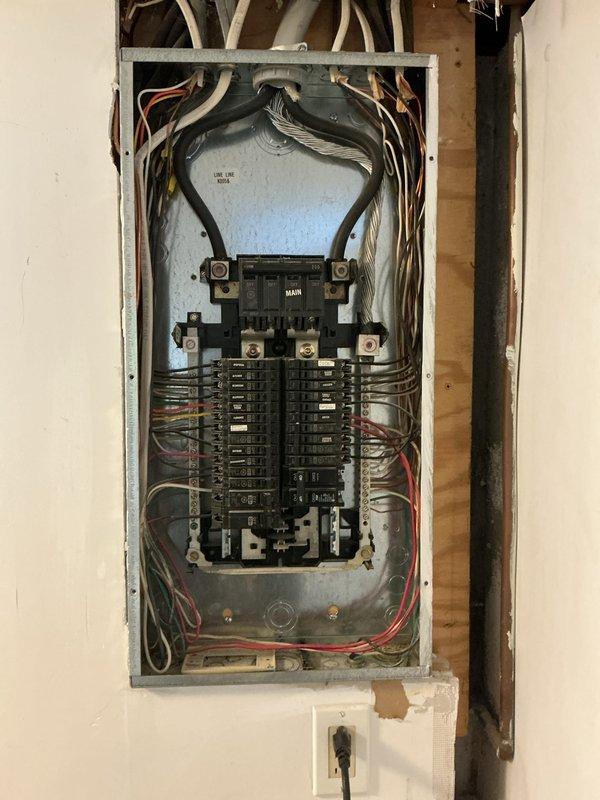 Conducted a thorough electrical inspection of the main breaker panel, documenting the condition of circuit breakers, wiring connections, and overall installation compliance. Additionally, examined the plumbing access panel containing a Sensus water meter, PVC piping, and shut-off valve, noting potential water damage on surrounding surfaces.