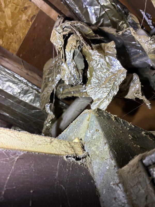 Performed diagnostic inspection on heating system and identified cracked heat exchanger in existing furnace. Documentation includes photos of the control panel/equipment setup in utility area and damaged insulation with torn foil covering in the ductwork. Customer was presented with replacement furnace options to address this critical safety issue.