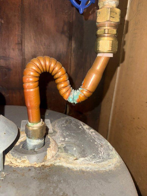 Conducted mid-morning inspection of dual Rheem water heater system. Observed significant corrosion and mineral buildup at connection points of the copper flex line, particularly at the U-bend section. Noted green-blue oxidation on brass fittings and documented condition of both units, including proper venting configuration and overall installation against wooden wall paneling. Photographic documentation completed.
