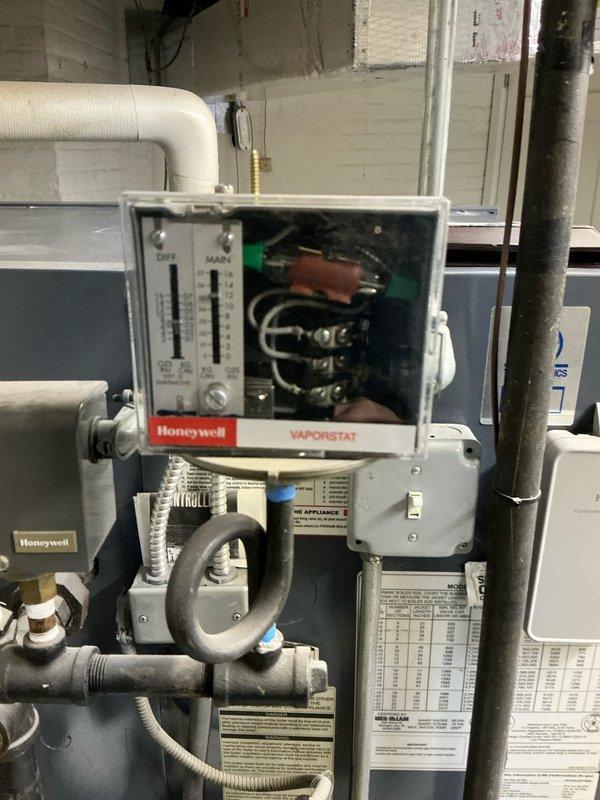 Conducted comprehensive inspection of aging boiler system with visible corrosion and rust staining on surrounding wall surfaces. Evaluated Honeywell VAPORSTAT control unit, noting condition of differential and main pressure gauges, wiring connections, and associated piping network. Provided customer with multiple replacement boiler options suitable for the existing configuration.