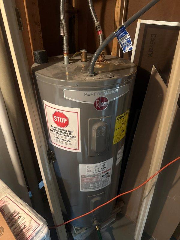 Conducted a plumbing inspection on a Rheem Performance water heater, documenting significant corrosion and deterioration at the braided metal hose connection point on top of the unit. Photographic documentation reveals extensive rust buildup, flaking material, and mineral deposits around the connection, suggesting potential failure risk requiring prompt attention.