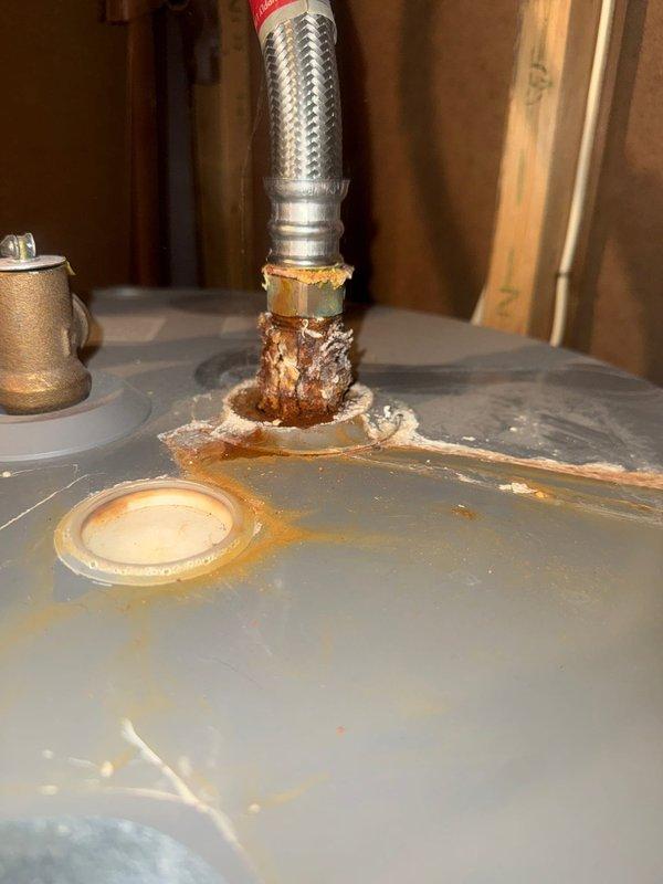 Conducted a plumbing inspection on a Rheem Performance water heater, documenting significant corrosion and deterioration at the braided metal hose connection point on top of the unit. Photographic documentation reveals extensive rust buildup, flaking material, and mineral deposits around the connection, suggesting potential failure risk requiring prompt attention.