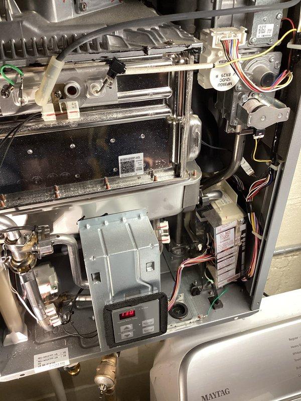 Diagnosed loud grinding noise in Rinnai tankless water heater during operation. Inspection revealed faulty flow control motor (MP36GU 12VDC) with worn components. Replaced flow control motor assembly and verified proper operation with no further noise during heating cycles.