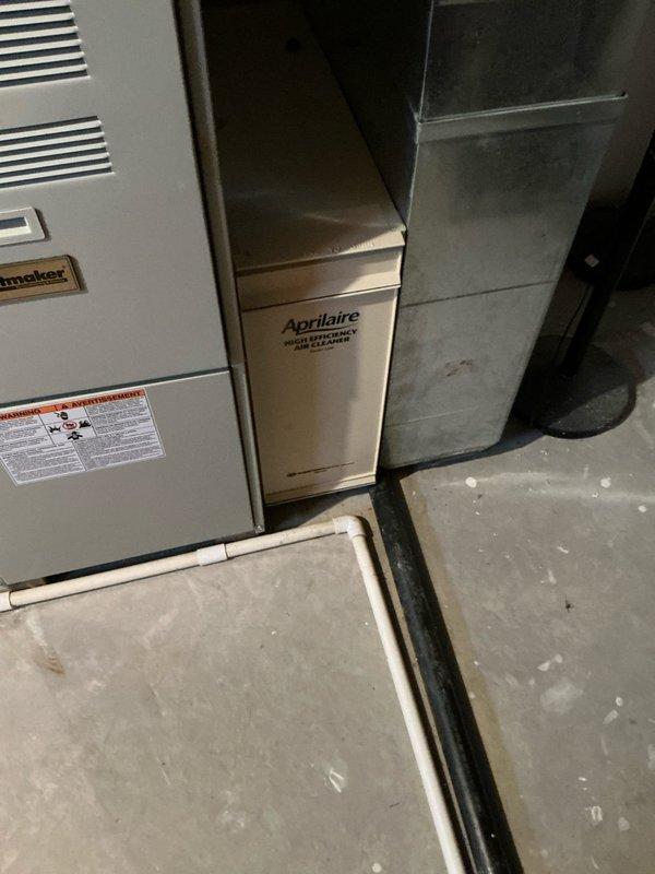 Conducted full system evaluation for basement HVAC replacement, presenting comprehensive options for furnace, ventilation, and air quality components. Documented existing installation which includes a furnace unit with PVC ventilation, attached Aprilaire high-efficiency air cleaner, and humidifier system. Photographed current setup to support replacement recommendations and ensure proper system sizing for the basement location.