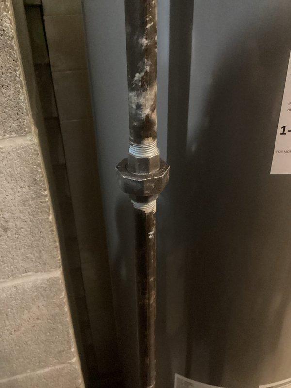 Responded to service call for a small gas leak in pipe running from near garage through the garage. Inspected outdoor gas meter which showed significant corrosion and rust at valve assembly and pipe joints. Further examination revealed deteriorated metal union connector on vertical pipe in utility space with visible threading issues and signs of previous maintenance attempts.