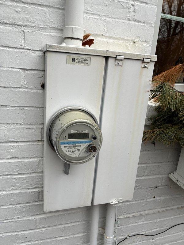 Conducted an assessment for furnace and full system replacement options, documenting the existing electrical meter configuration and current HVAC system. Evaluation included inspection of the beige air handler unit with Honeywell controls mounted against gray walls, noting the condition of ductwork connections and supporting framework for proper replacement specifications.