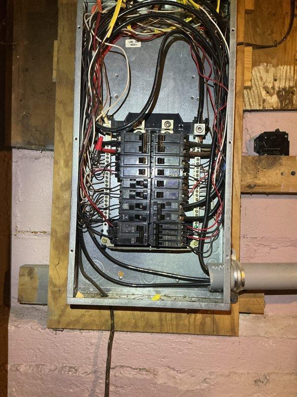 Conducted electrical inspection of residential circuit breaker panel. Documented existing panel configuration with approximately 20 breakers and noted multiple wire bundles requiring organization. Also observed nearby water damage and mineral deposits in utility area that may present potential electrical hazards.