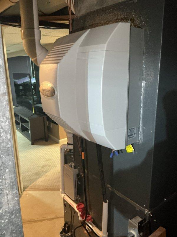Completed scheduled maintenance on two heating systems. Inspected and serviced a water heater system with connected copper piping and exhaust ventilation, confirming proper installation and operation. Also performed maintenance on an Aprilaire whole-home humidifier unit mounted adjacent to the HVAC system, verifying all components were functioning correctly and properly connected to the ductwork.