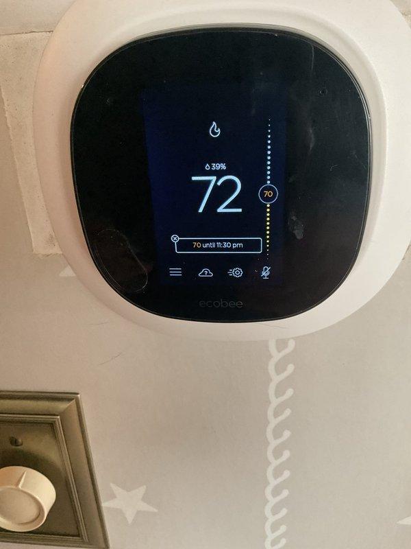 Responded to service call for non-functioning thermostat. Diagnosed and replaced faulty Ecobee smart thermostat with new unit. Successfully calibrated system and verified proper heating function with temperature display showing accurate readings and flame icon indicating normal operation.