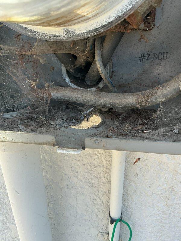 Conducted electrical inspection of HVAC system components, documenting significant rust and corrosion on metal brackets and mounting hardware. Observed improper wiring connections with accumulated dust and cobwebs, particularly around the #2.8CU marked area, indicating maintenance issues requiring attention.