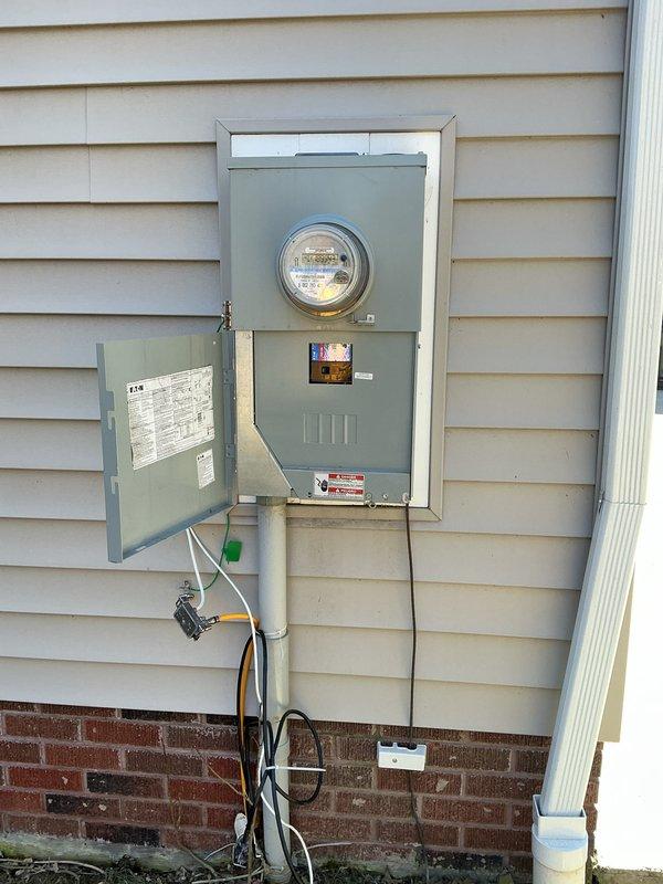 Conducted visual inspection of residential electrical system, documenting main breaker panel configuration with approximately 20-30 circuit breakers and associated wiring. Examined exterior meter installation, noting digital display functionality and connection points to service entrance conductors.