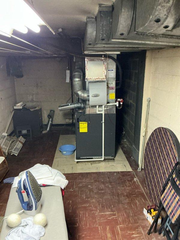 Conducted assessment of HVAC system with inoperable furnace and water heater due to compromised chimney liner causing severe leakage into the heating system. Inspection revealed water damage to the utility area with visible staining on cinder block walls and evidence of moisture affecting the mechanical components. Presented replacement options for both heating system and water heater that would address the chimney liner compatibility issues.