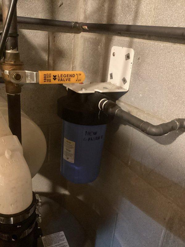 Conducted on-site estimate for water heater replacement. Inspected existing Richmond water heater showing signs of age with handwritten markings. Evaluated current installation including copper and PVC piping connections, water filter system with blue cartridge, and associated brass valves. Documented complete setup with photos for accurate replacement specifications and potential upgrades.