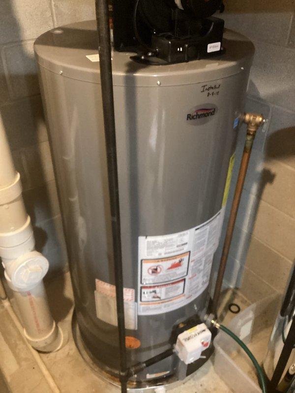 Conducted on-site estimate for water heater replacement. Inspected existing Richmond water heater showing signs of age with handwritten markings. Evaluated current installation including copper and PVC piping connections, water filter system with blue cartridge, and associated brass valves. Documented complete setup with photos for accurate replacement specifications and potential upgrades.