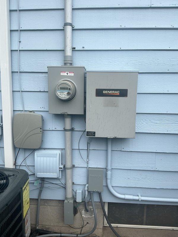 Conducted comprehensive electrical inspection of a residential installation featuring a Generac transfer switch and digital electric meter mounted on the exterior wall, with all components connected via proper conduit piping. Interior inspection of the circuit breaker panel revealed standard configuration with main breaker and multiple circuits, with all wiring connections appearing to be in good working condition. Photographic documentation was completed for service records.