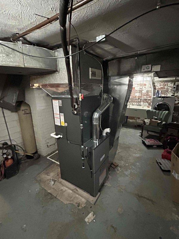Completed installation of a new 80% efficient furnace, air conditioning system, and 50-gallon hot water tank in customer's basement utility area. System includes properly insulated copper refrigerant lines connected to the outdoor condensing unit with brass valve assembly, and new metal ductwork installed along the ceiling. All components were tested, properly secured, and confirmed operational before completion.