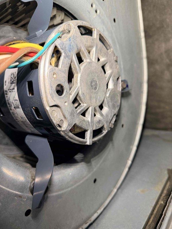 Performed scheduled heating maintenance on aging system (10+ years old). Inspected blower motor assembly which showed signs of normal wear, including dusty components and slight corrosion on mounting bracket. All electrical connections to motor remain intact with proper wire routing through ventilation housing.