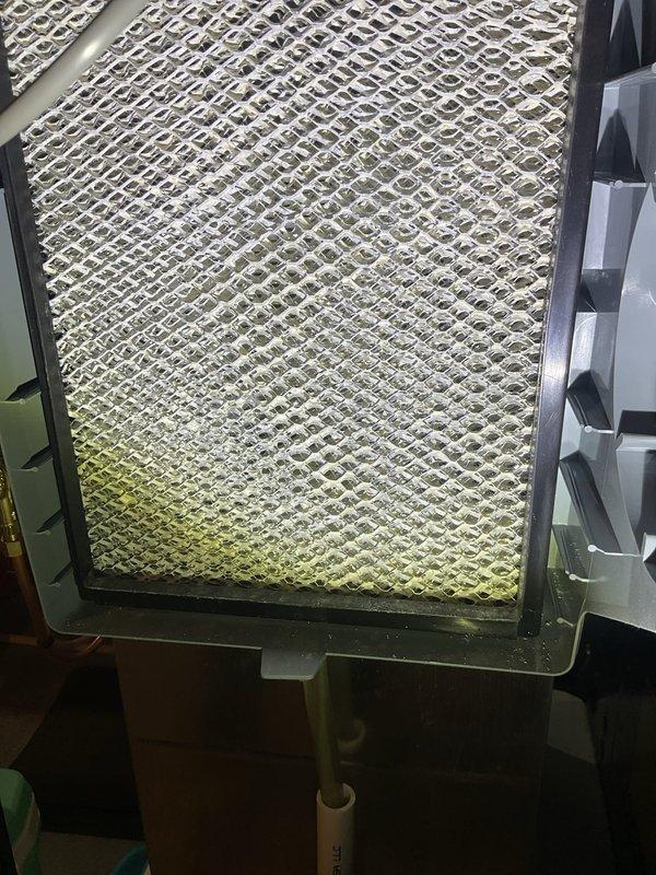 Performed scheduled heating maintenance service on furnace system. Inspected and documented condition of air filter showing moderate dust accumulation with yellow discoloration concentrated at lower portion. Examined evaporator coil housing and filter assembly, noting proper installation of diamond-pattern filtration media within metal frame housing.
