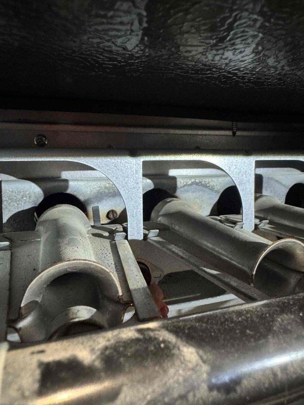 Performed routine maintenance on a 10+ year old heating system, inspecting the burner assembly and heat exchanger. System appears to be from July 2013 based on manufacturer date stamp, showing normal wear but remaining in operational condition. Documented current state with photos for service records.